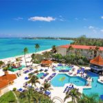 An aerial view of a resort with a pool and beach. by Chasing the Sun Vacations