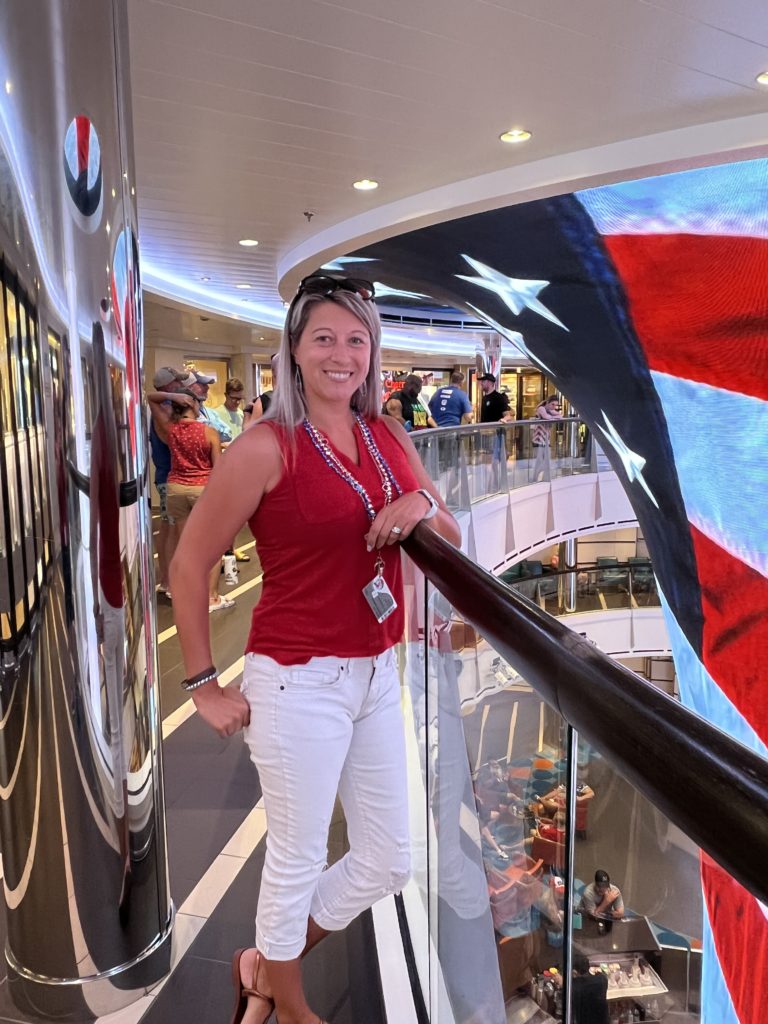 A woman standing in front of an American flag representing a Travel Advisor. by Chasing the Sun Vacations