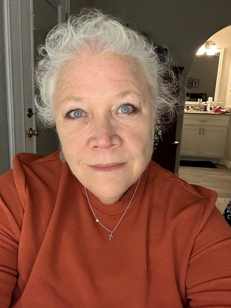 A woman in an orange shirt is capturing a selfie while on a cruise. by Chasing the Sun Vacations