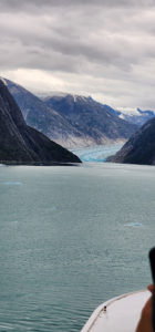 A person is taking a picture of a glacier from a boat. by Chasing the Sun Vacations