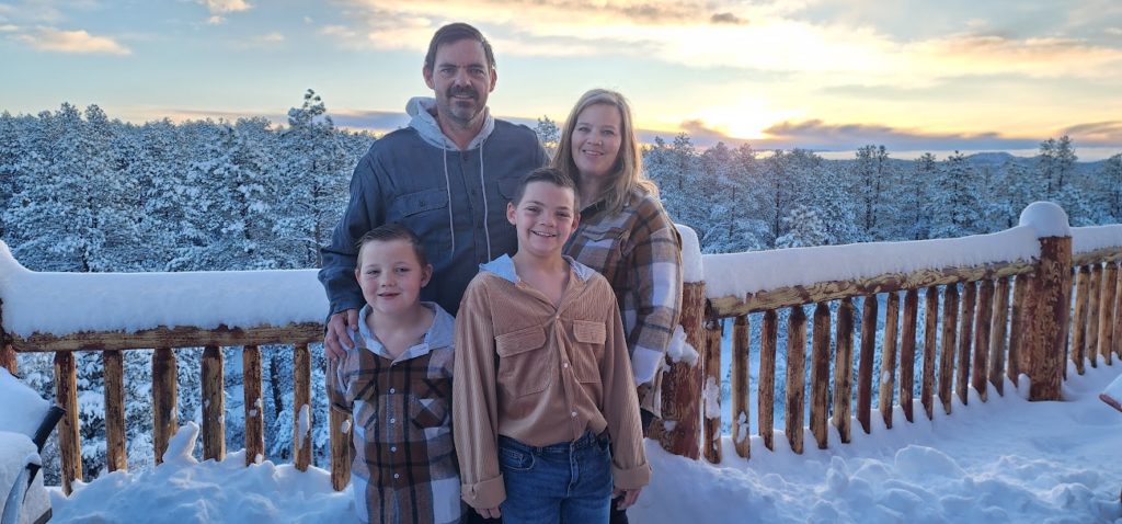 A family is posing for a photo on a deck in the snow. by Chasing the Sun Vacations