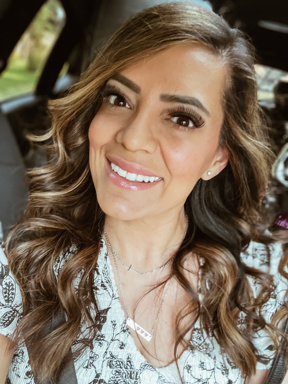 A smiling woman with curled hair taking a selfie inside a vehicle. by Chasing the Sun Vacations